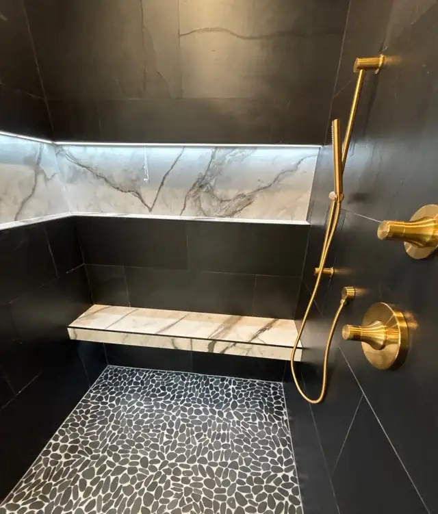 Walk-in shower with a backlit marble niche, floating stone bench, pebble floor and unlacquered brass fittings in Wellington, FL