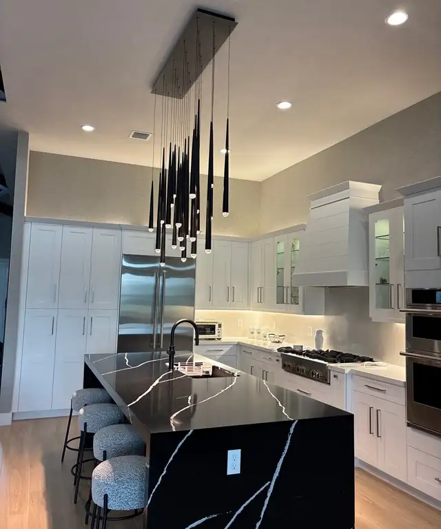 Palm Beach Gardens kitchen remodel with white shaker cabinetry, a black quartz waterfall island and a cascading pendant cluster