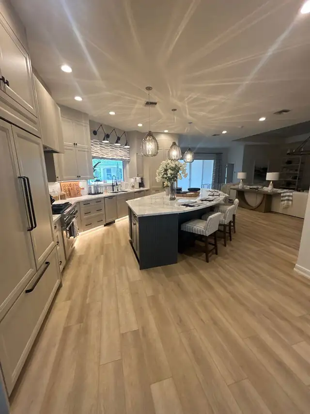 Open kitchen with a large island, counter seating and layered pendant lighting over wood-look floors